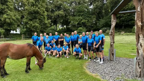 Groepsfoto van de toerleden op een grasveld tijdens de Teutotocht, met een paard op de voorgrond
